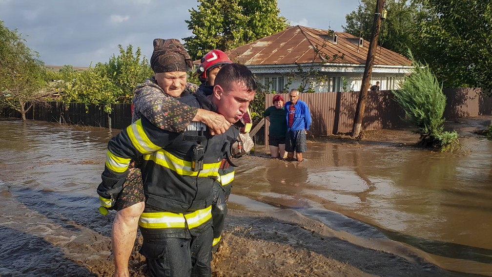 Um socorrista carrega uma mulher nas costas numa área inundada em Pechea, na Romênia, neste sábado, 14 de setembro de 2024. — Foto: Serviços de Emergência Romenos, ISU Galati via AP