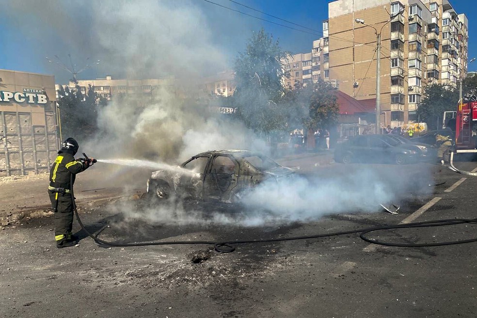 Bombeiros apagam um carro em chamas no pátio de um prédio de apartamentos após um ataque de mísseis das Forças Armadas da Ucrânia. — Foto: Canal do Telegram do governador da região de Belgorod, Vyacheslav Gladkov, via AP
