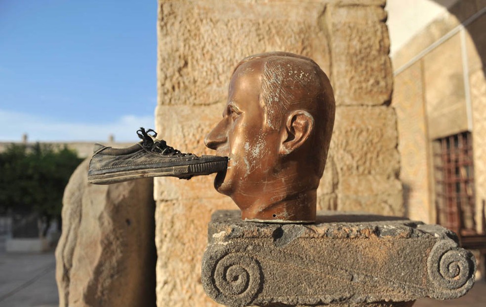 Um sapato é colado na boca de uma estátua do falecido presidente da Síria Hafez al-Assad, no museu de Maaret al-Numan, em 2016 — Foto: Bulent Kilic/AFP