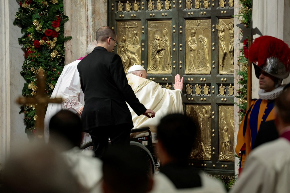 Sentado em uma cadeira de rodas, Papa Francisco abre as portas da Basílica de São Pedro, no Vaticano — Foto: REUTERS/Remo Casilli/Pool