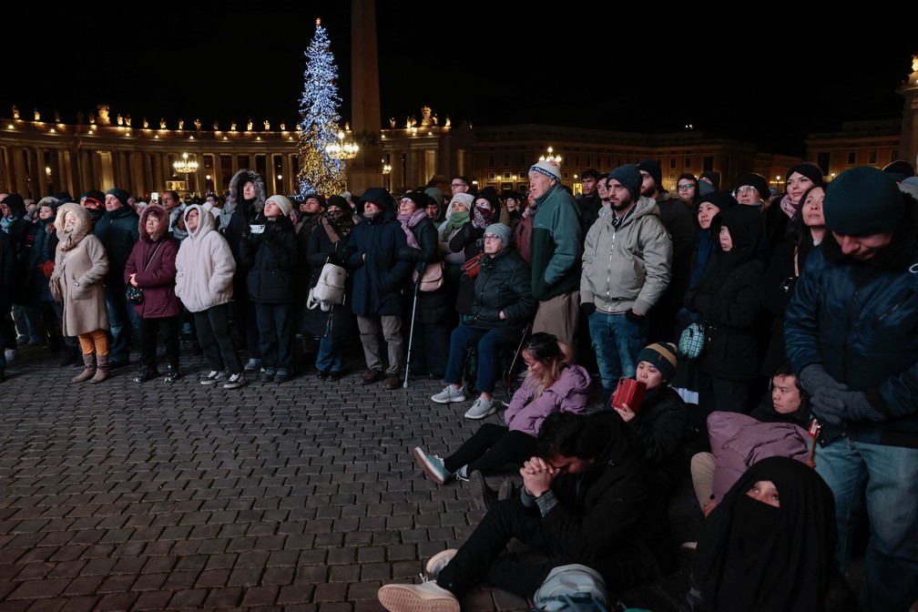 Fiéis orando e assistindo à Missa do Galo na Praça de São Pedro, no Vaticano — Foto: REUTERS/Remo Casilli