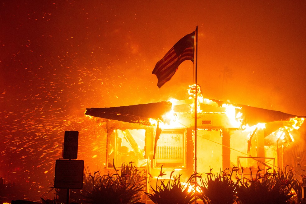 Casa com bandeira dos EUA na frente pega fogo em Los Angeles, na Califórnia, em 7 de janeiro de 2025. — Foto: REUTERS/Ringo Chiu TPX IMAGES OF THE DAY