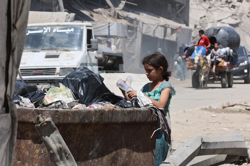 Menina revira lixo no bairro de Sheikh Radwan, na Cidade de Gaza, em meio a ofensiva de Israel nos arredores da cidade em 24 de agosto de 2025 — Foto: Omar al-Qattaa/AFP