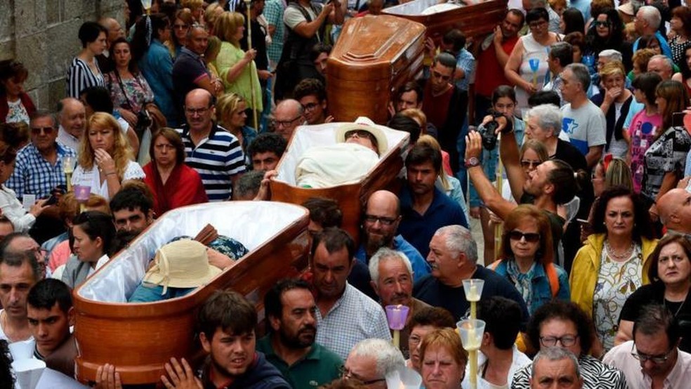 Pessoas levam nos ombros caixões com pessoas vivas no seu interior, durante a procissão de Santa Marta de Ribarteme, em 2019 — Foto: Miguel Riopa/AFP via Getty Images/BBC