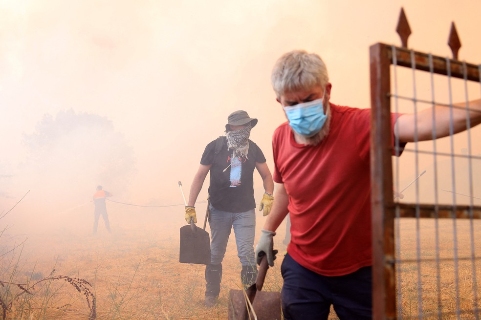 Pessoas usam coberturas faciais enquanto um incêndio florestal assola Veiga das Meas, perto de Verin, província de Ourense, Galícia, na Espanha. — Foto: Reuters/Nacho Doce