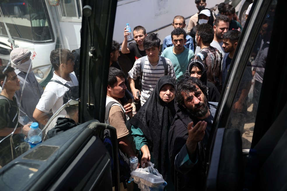 Afegãos deportados do Irã esperam para embarcar em ônibus que os levará de volta a território afegão, em agosto de 2025. — Foto: Sayed Hassib/ Reuters