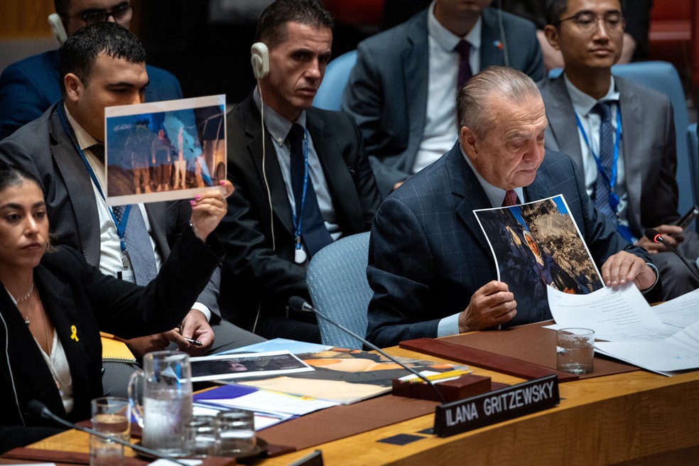Ilana Gritzewsky, à esquerda, ex-refém do Hamas, segura uma foto dela e de seu parceiro em protesto enquanto o embaixador argelino nas Nações Unidas, Amar Bendjama, fala sobre Maryam Abu Daqqa, uma das jornalistas mortas em Gaza, ao discursar no Conselho de Segurança das Nações Unidas — Foto: REUTERS/Angelina Katsanis