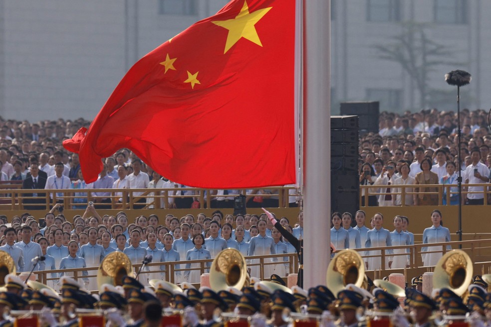 Pessoas participam de uma cerimônia de hasteamento de bandeira durante um desfile militar para marcar o 80º aniversário do fim da Segunda Guerra Mundial, em Pequim, China, 3 de setembro de 2025 — Foto: REUTERS/Tingshu Wang