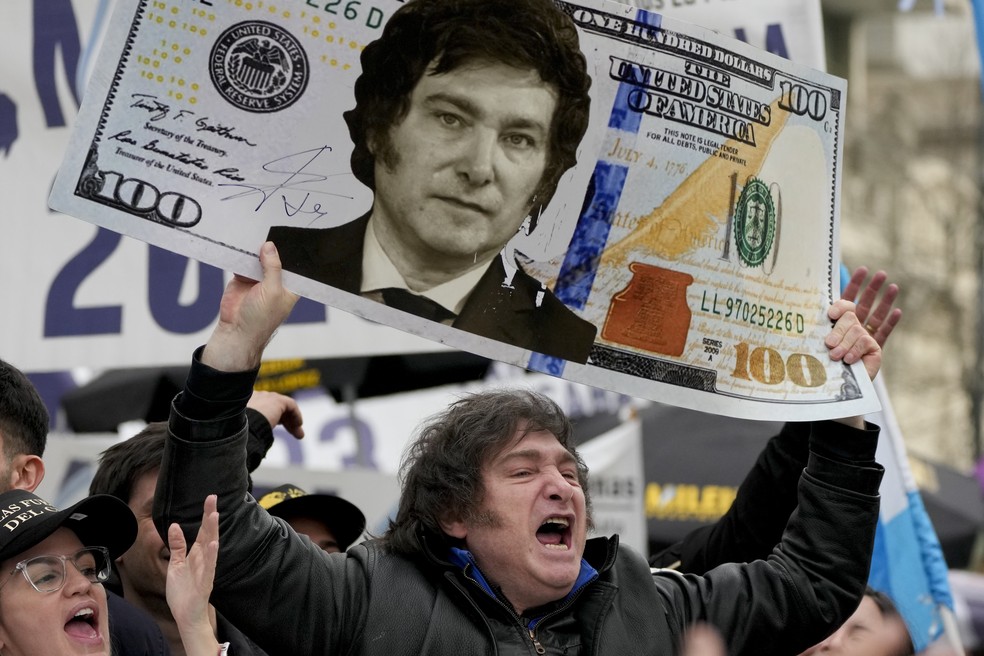 Javier Milei, à época candidato à presidência da Argentina, ergue uma nota de dólar com seu próprio rosto — Foto: Natacha Pisarenko/AP