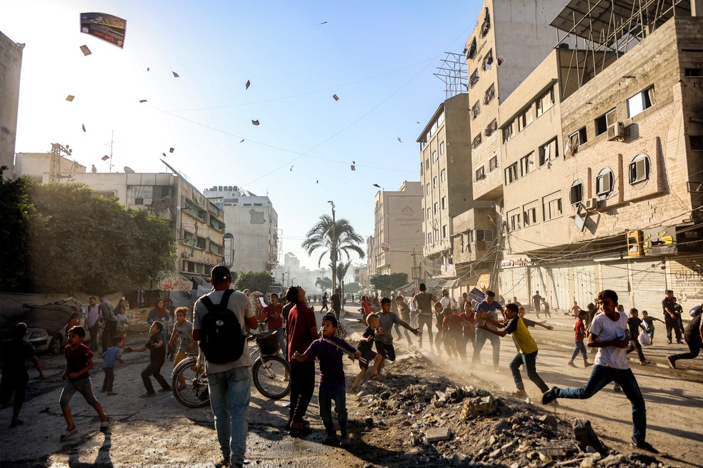 Palestinos da Cidade de Gaza observam panfletos jogados pelo Exército israelense com ordens de evacuação em 9 de setembro de 2025. — Foto: Omar Al-Qattaa/AFP
