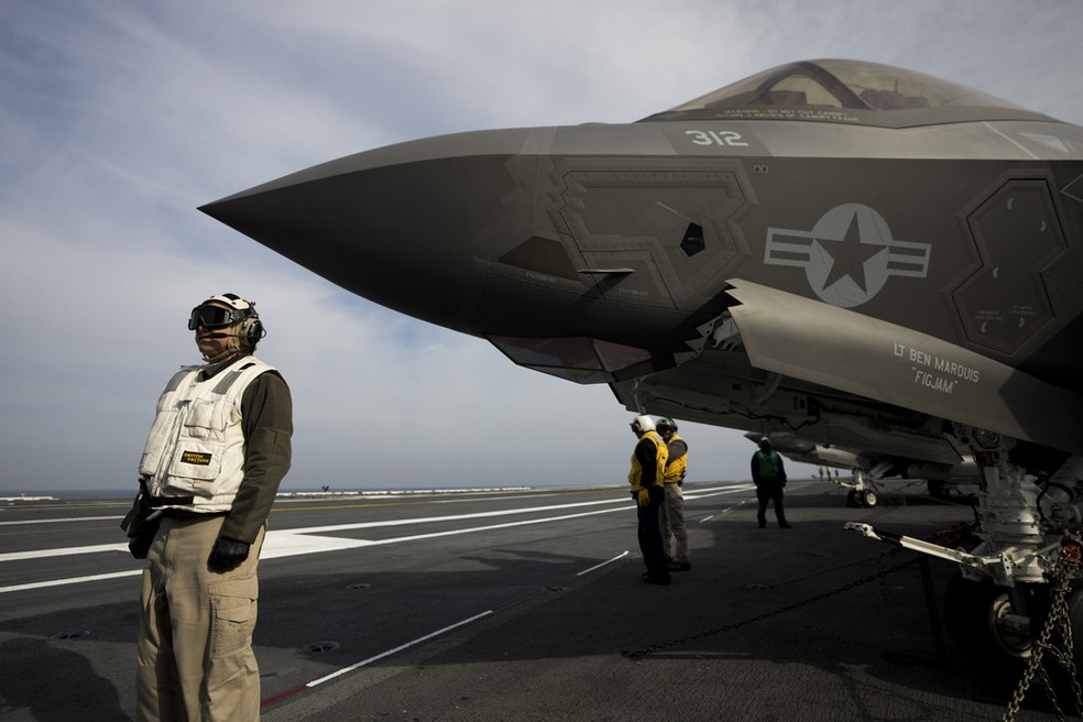 Militares da Marinha dos EUA se posicionam no entorno de um caça F-35, no porta-aviões USS George Washington — Foto: Victor R. Caivano/AP Photo