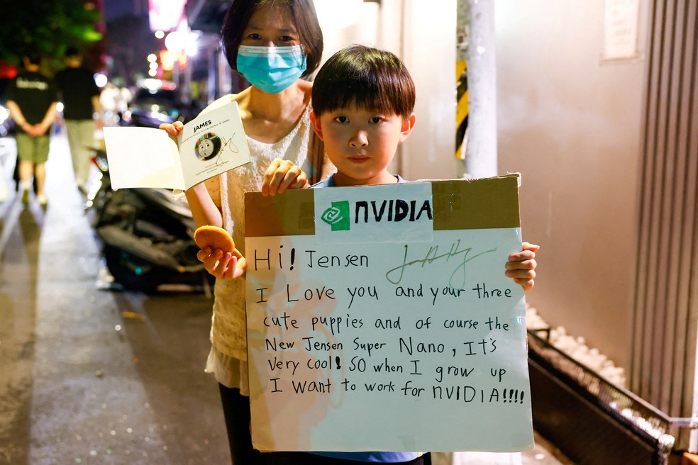 Criança segura cartaz dizendo 'Jensen, eu te amo', do lado de fora de um restaurante onde o fundador da Nvidia jantou, em Taiwan, em maio deste ano — Foto: Ann Wang/Reuters