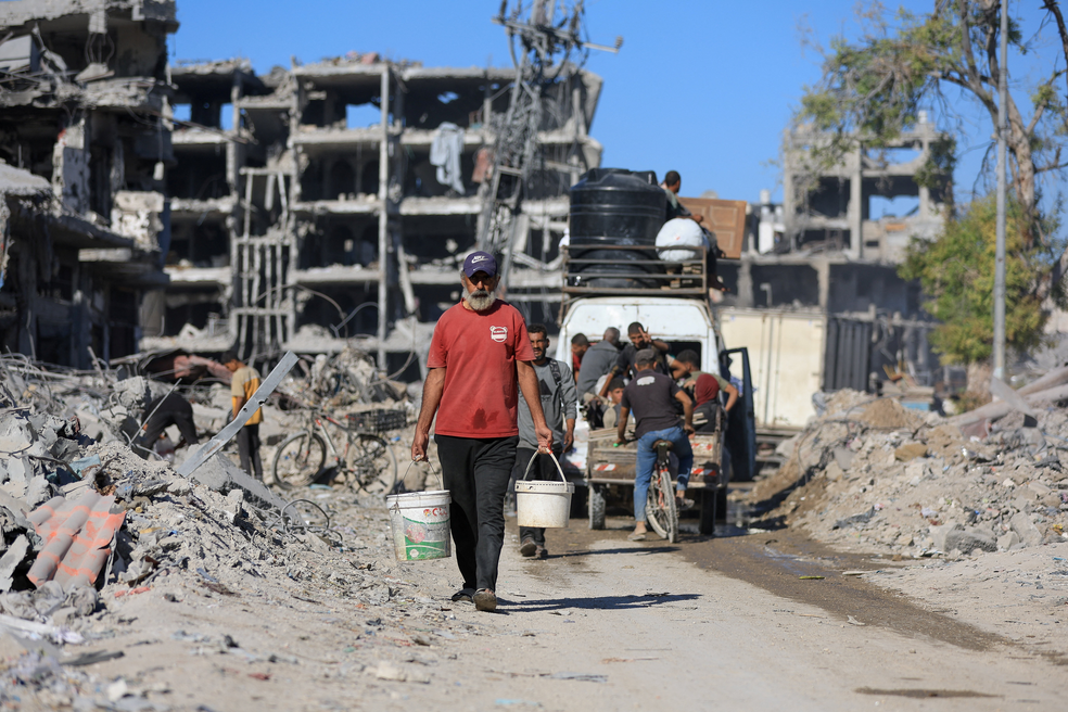 Palestinos passam pelos escombros de prédios destruídos, em meio a um cessar-fogo entre Israel e o Hamas, na Cidade de Gaza , em 14 de outubro de 2025 — Foto: REUTERS/Dawoud Abu Alkas