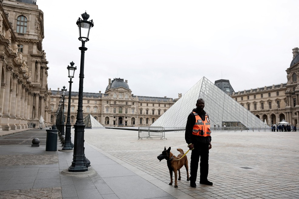 Segurança com cão de guarda próximo à Pirâmide de vidro do Museu do Louvre após roubo de joias em 20 de outubro de 2025. — Foto: REUTERS/Benoit Tessier