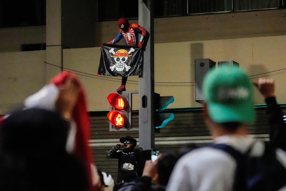 Um manifestante vestindo uma fantasia de Homem-Aranha segura bandeira de 'One Piece' durante manifestação em Lima, no Peru, em 28 de setembro de 2025 — Foto: Angela Ponce/Reuters