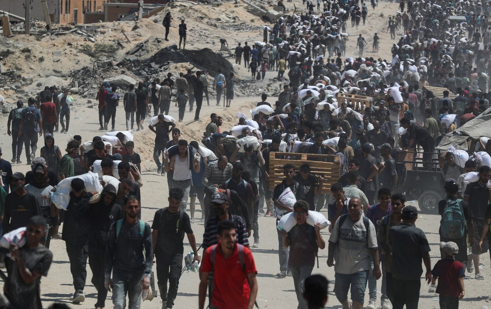 Palestinos carregam suprimentos de ajuda humanitária em Gaza — Foto: Mahmoud Issa/Reuters