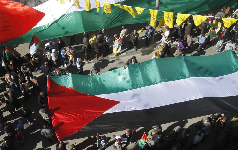 Pessoas marcham com bandeiras gigantes da Palestina durante uma manifestação de apoio a candidatura palestina da ONU — Foto: Nasser Shiyoukhi/AP