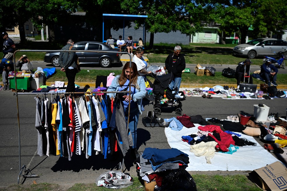 Uma mulher observa roupas de segunda mão à venda em um mercado de rua em Villa Fiorito, nos arredores de Buenos Aires. — Foto: LUIS ROBAYO/AFP