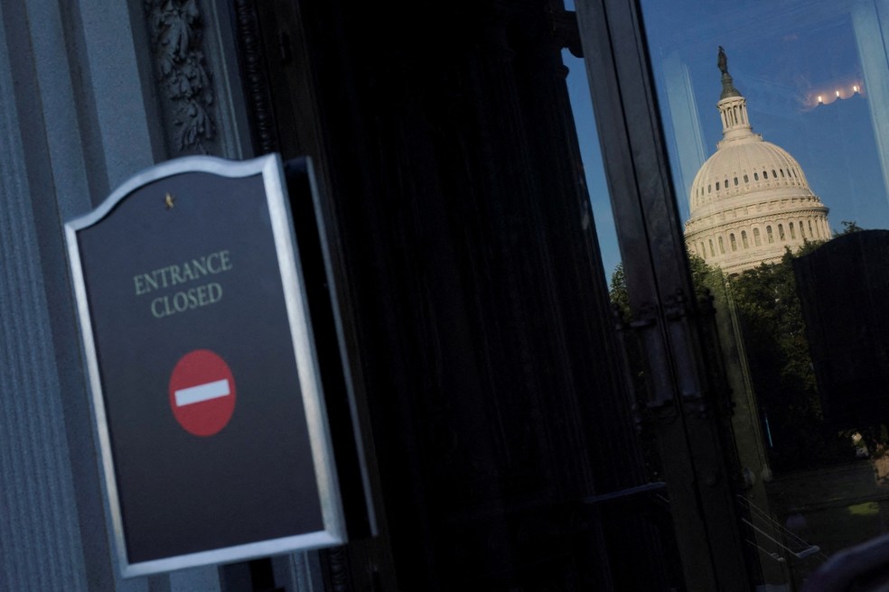 Cúpula do Capitólio refletida na porta de vidro da Biblioteca do Congresso americano, com placa de "entrada fechada" no primeiro dia de paralisação do governo dos Estados Unidos em 1° de outubro de 2025. — Foto: REUTERS/Nathan Howard