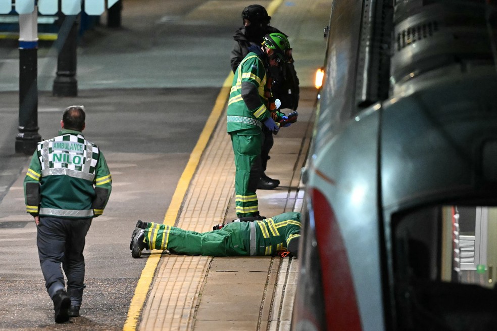 Policiais revistam os trilhos na Estação Huntingdon, no leste da Inglaterra, em 1º de novembro de 2025, após um ataque a facas — Foto: Justin Tallis/AFP