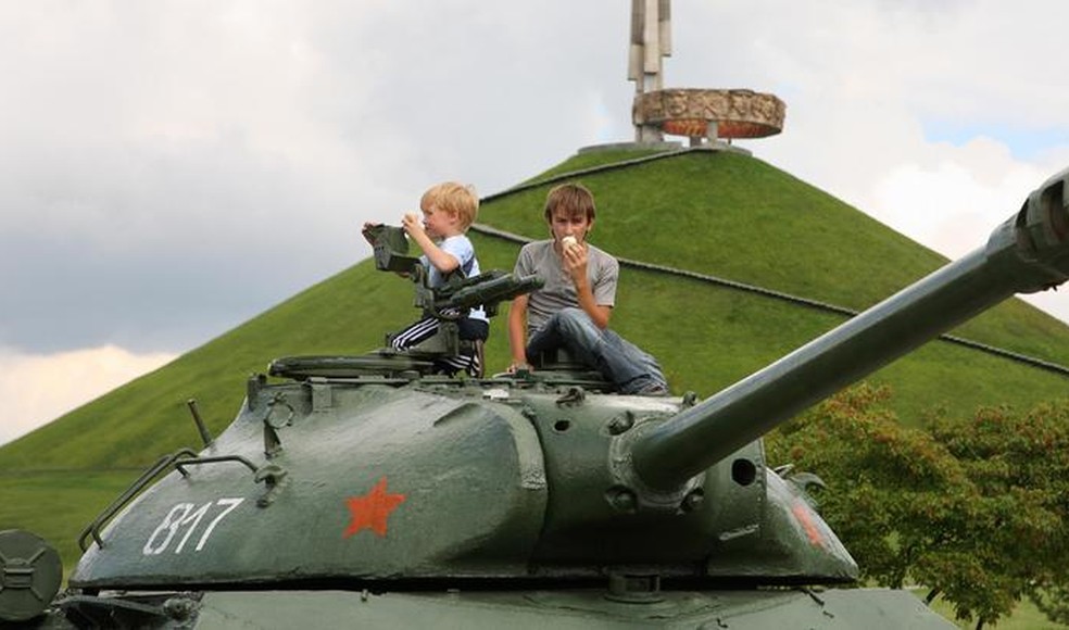 Crianças em um tanque de guerra em monumento em homenagem ao exército soviético perto de Minsk. — Foto: Caro/picture alliance via DW