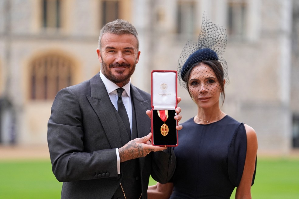 Ex-jogador de futebol David Beckham posa com título de cavaleiro ao lado da esposa, Victória Beckham, após cerimônia no castelo de Windsor, no Reino Unido, em 4 de novembro de 2025. — Foto: Andrew Matthews/Pool via REUTERS