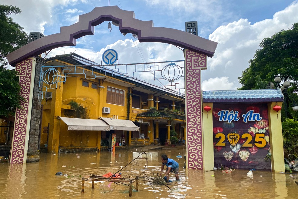 Homem coleta com a mão galhos em área inundada em Hoi An, na região central do Vietnã, em 30 de outubro de 2025. — Foto: Thinh Nguyen/ Reuters