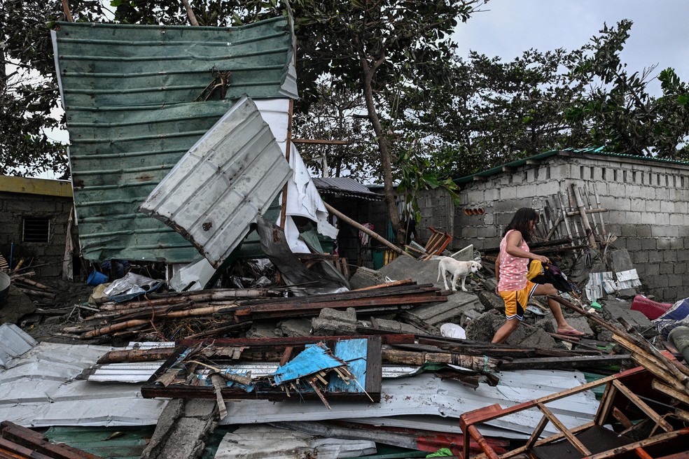 Uma mulher caminha sobre uma casa danificada pela ressaca após o tufão Fung-wong atingir a costa da cidade de Bonuan, Pangasinan, Filipinas. — Foto: Noel Celis/Reuters