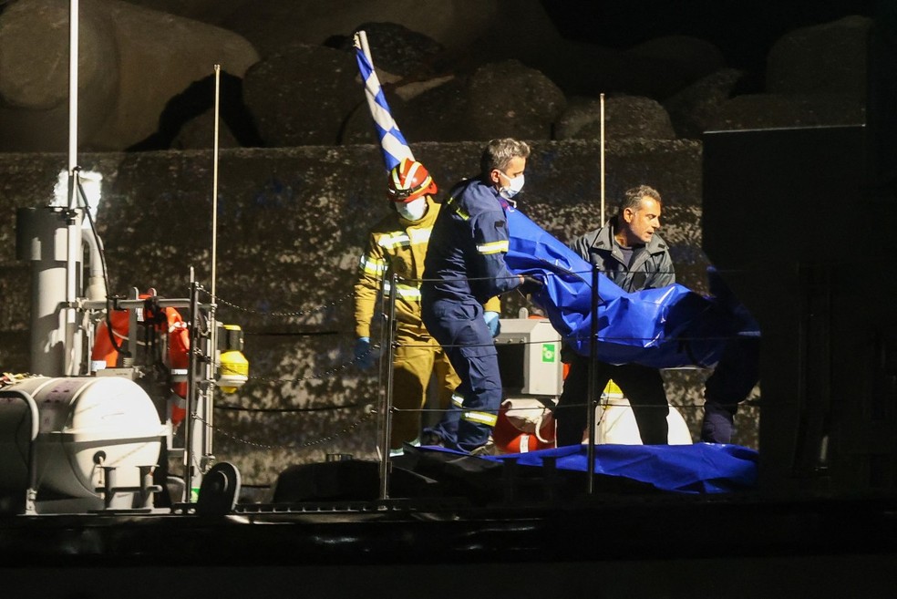 Bombeiros carregam corpos após o naufrágio de um barco de migrantes perto do porto de Ierapetra, na ilha de Creta — Foto: COSTAS METAXAKIS / AFP