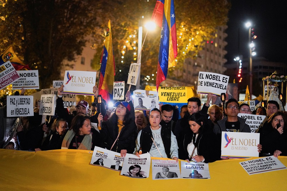 Venezuelanos exibem cartazes e bandeiras durante uma marcha global em apoio à ganhadora do Prêmio Nobel da Paz, Maria Corina Machado, em Madri, Espanha, em 6 de dezembro de 2025. — Foto: REUTERS/Ana Beltran