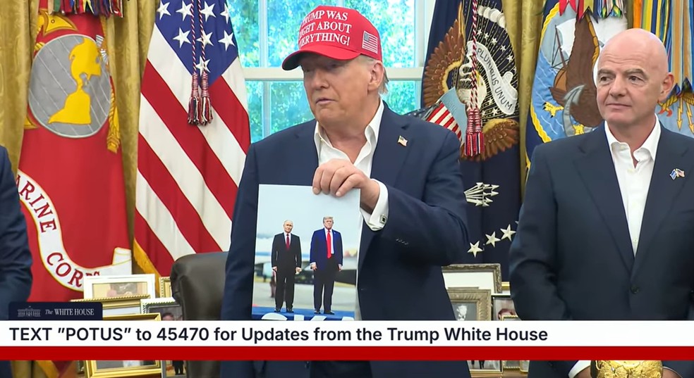O presidente americano, Donald Trump, mostra uma foto dele ao lado de Vladimir Putin, presidente russo. — Foto: Reprodução/White House