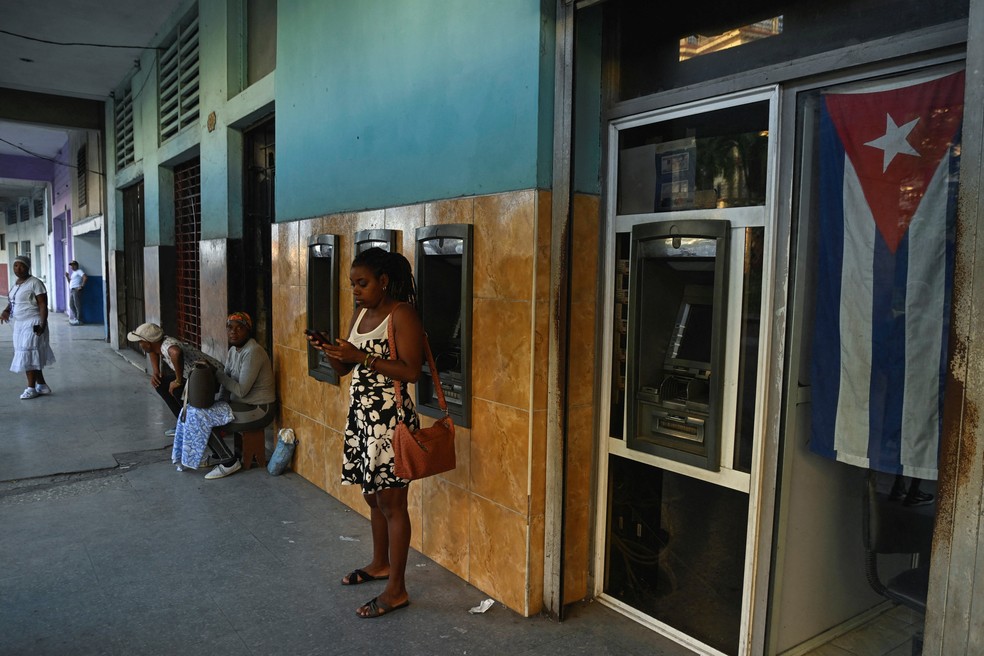Uma mulher usa o celular do lado de fora de um banco em meio a um colapso parcial da rede elétrica em Havana, Cuba, em 3 de dezembro de 2025. — Foto: Reuters