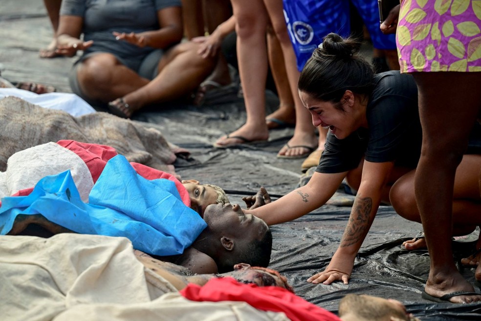 ATENÇÃO, IMAGENS FORTES: Mulher chora ao lado de corpo de morto durante megaoperação no Rio; corpos foram estendidos na Praça São Lucas, na favela Vila Cruzeiro, no Complexo da Penha, no Rio de Janeiro, Brasil, em 29 de outubro de 2025. — Foto: Pablo Porciuncula/AFP