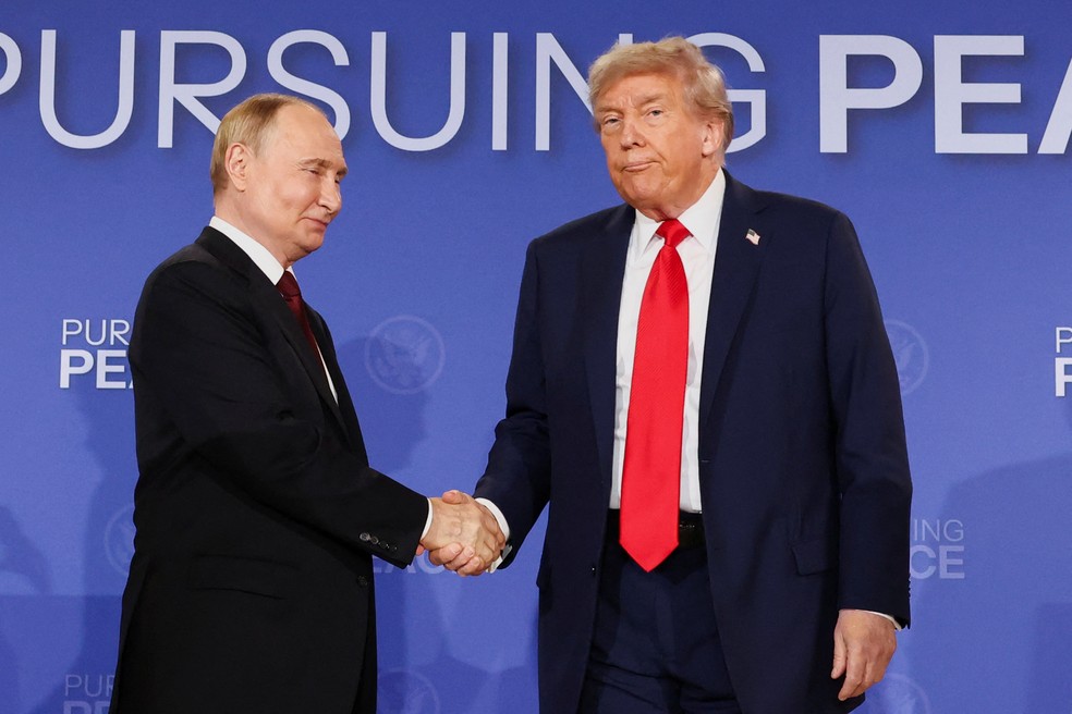 ARQUIVO: Putin e Trump se cumprimentam após discurso no Alasca, em agosto de 2025 — Foto: REUTERS/Kevin Lamarque