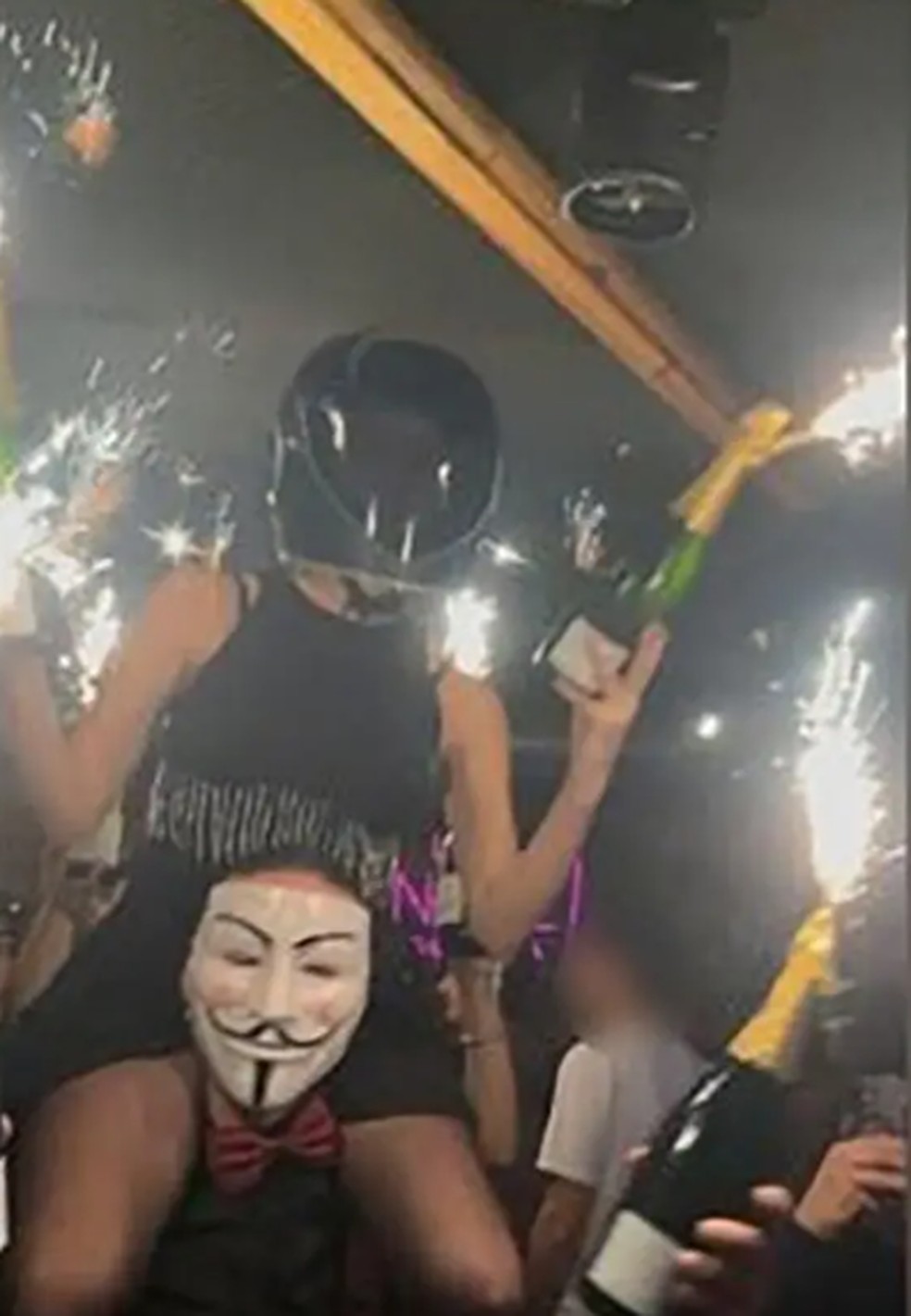 Mulher nos hombros de um funcionário do bar Le Constellation, na Suíça, ergue bebida com sinalizador perto do teto do bar, que pegou fogo em 1º de janeiro de 2026 — Foto: Reprodução/ Redes sociais