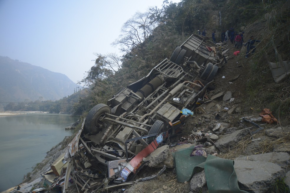 Os destroços de um ônibus são vistos na margem do rio Trishuli, após o veículo ter saído da pista em uma rodovia montanhosa perto de Benighat, a oeste da capital, Katmandu, Nepal, na segunda-feira, 23 de fevereiro de 2026 — Foto: Foto AP/Bijay Rai