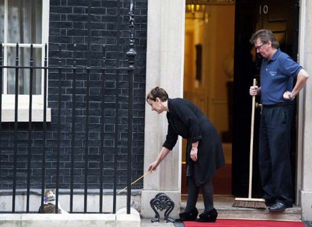Funcionários da casa oficial do premiê britânico, David Cameron, tentam pegar o gato Larry, que se escondeu atrás de grades, em foto de 2016 — Foto: Ki Price/AFP