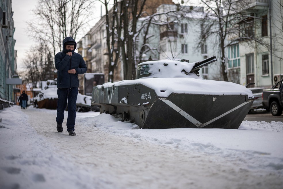 Uma pessoa caminha ao lado de um veículo blindado russo capturado em meio à invasão russa da Ucrânia. — Foto: HENRY NICHOLLS/AFP