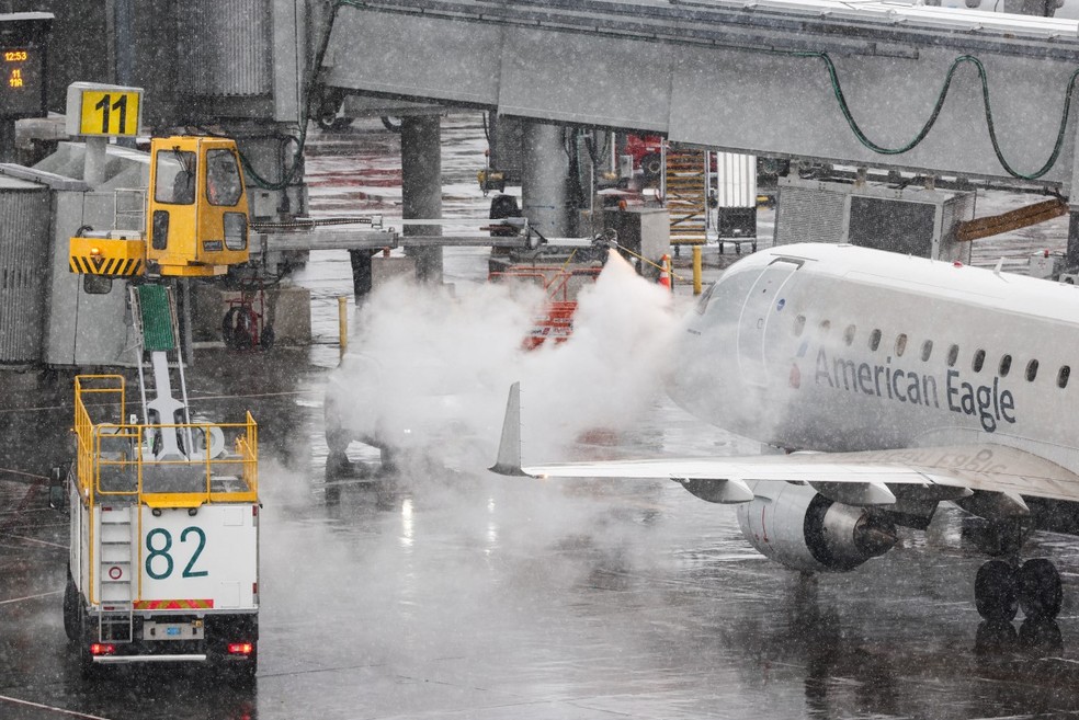 Uma equipe de solo realiza a retirada de gelo de um avião de passageiros Embraer ERJ-175 da American Eagle no Aeroporto LaGuardia, em Nova York, em 22 de fevereiro de 2026. — Foto: CHARLY TRIBALLEAU / AFP