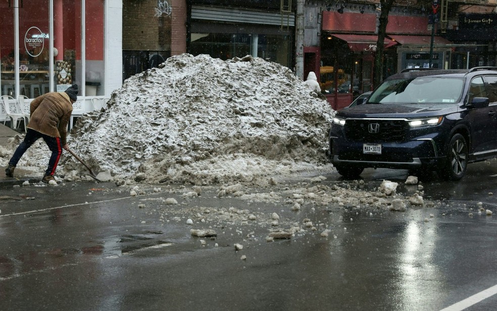 Um homem remove com uma pá uma pilha de neve da recente tempestade, antes da chegada de uma nova grande tempestade de inverno em Nova York, em 22 de fevereiro de 2026. — Foto: TIMOTHY A.CLARY / AFP