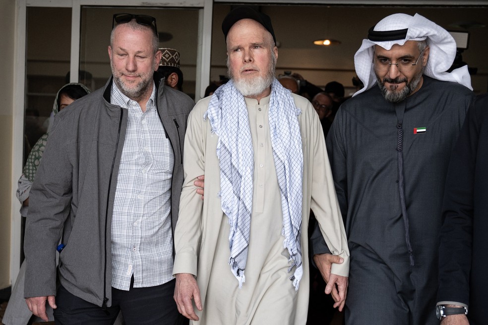 O cidadão americano Dennis Coyle (C), após ser libertado pelo Talibã, caminha com o embaixador dos Emirados Árabes Unidos em Cabul, Saif Mohammed Al-Ketbi — Foto: Wakil Kohsar / AFP