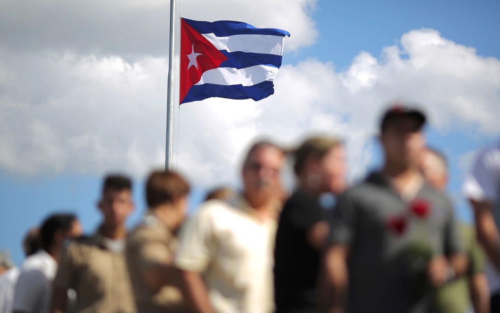 Uma bandeira de Cuba a meio mastro é vista enquanto pessoas aguardam em fila para homenagear o ex-presidente Fidel Castro em Havana — Foto: Carlos Barria/Reuters