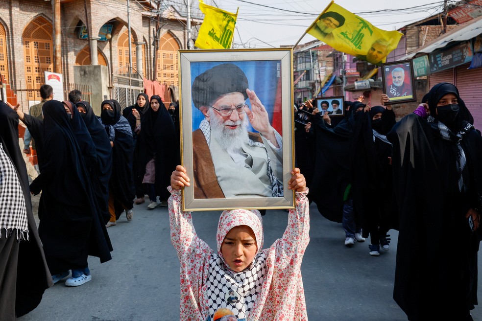 Mulher xiita levanta foto de ex-líder supremo iraniano Ali Khamenei, morto em bombardeios dos EUA e de Israel, durante protesto em 4 de março de 2026. — Foto: REUTERS/Sharafat Ali