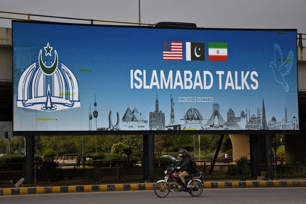 Cartaz em rua de Islamabad, no Paquistão, anuncia as conversas entre Estados Unidos e Irã, que serão sediadas na cidade, em 10 de abril de 2026. — Foto: Waseem Khan/ Reuters