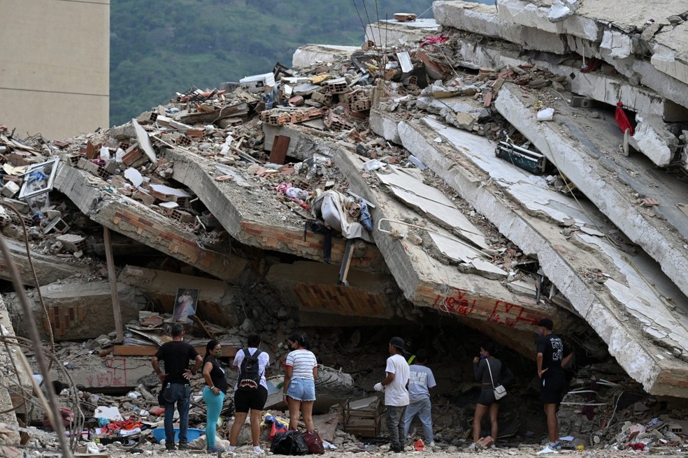 Em Caraballeda, estado de La Guaira, Venezuela, em 9 de julho de 2026, pessoas aguardam notícias de parentes que se acredita estarem presos sob os escombros após os terremotos de 24 de junho. — Foto: RAUL ARBOLEDA / AFP