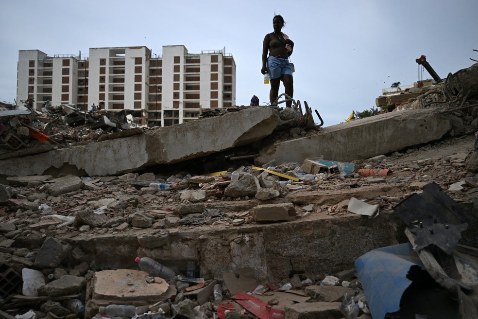 Uma mulher está em pé sobre os escombros de um prédio que desabou em Caraballeda, estado de La Guaira, Venezuela, em 9 de julho de 2026 — Foto: RAUL ARBOLEDA / AFP