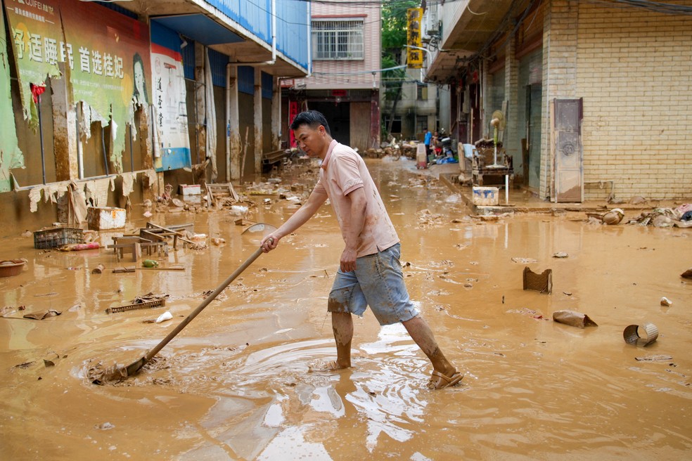 Homem remove lama de rua após fortes chuvas provocadas pelo tufão Maysak na cidade de Sanli, em Guangxi Zhuang, na China, em 9 de julho de 2026. — Foto: cnsphoto via REUTERS