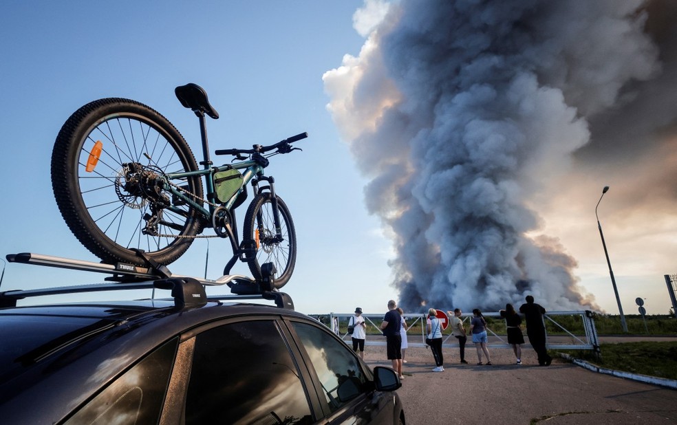 Testemunhas observam a fumaça de um incêndio em um centro logístico da varejista russa Wildberries, em Elektrostal, nos arredores de Moscou, em 18 de julho de 2026. — Foto: TATYANA MAKEYEVA / AFP
