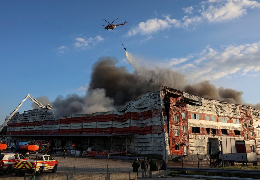 Um helicóptero de combate a incêndios lança água sobre o local de um ataque de míssil russo, em meio ao ataque da Rússia à Ucrânia, na região de Kiev, Ucrânia — Foto: REUTERS